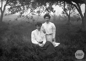 Two Young Women Sitting Besides Each Other in Misty Overgrown Field of Grass, Early 1900s