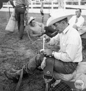 A cowboy does a tune-up while enjoying a cigar.