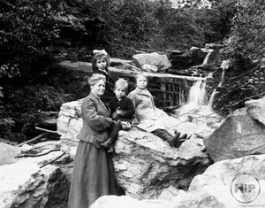 Middle-Aged Woman and Three Angelic Young Children Posing by Calming Creekside