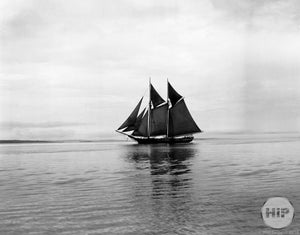 Double-Masted Schooner with Dark Sails Travelling through the Calm, Foggy Waters of MA
