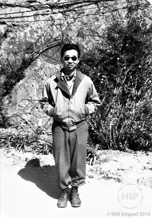 George Sakata in Sunglasses and Casual Wear Smiling and Posing in Front of Woodland Area