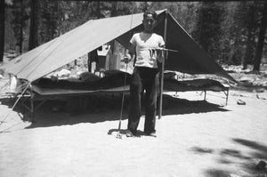 Photograph of Youth Displaying a Proud Catch of Fingerling Fish in Front of Campsite about 1950