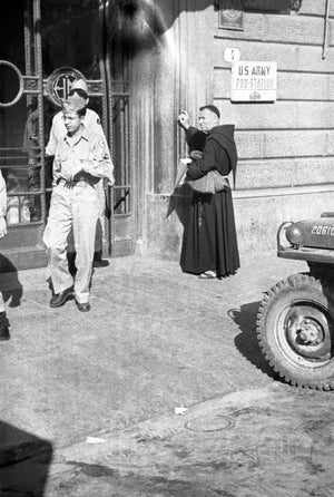 A monk watches a group of passing soldiers in Italy, 1940s