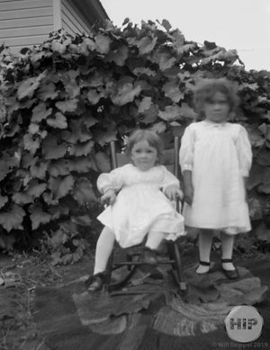 A snapshot of two girls on grass and rug, courtesy of the Fred Bodin collection.