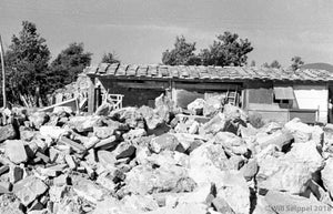 Rock Settlement in Shambles in Front Yard of Single-Story Log Cabin House